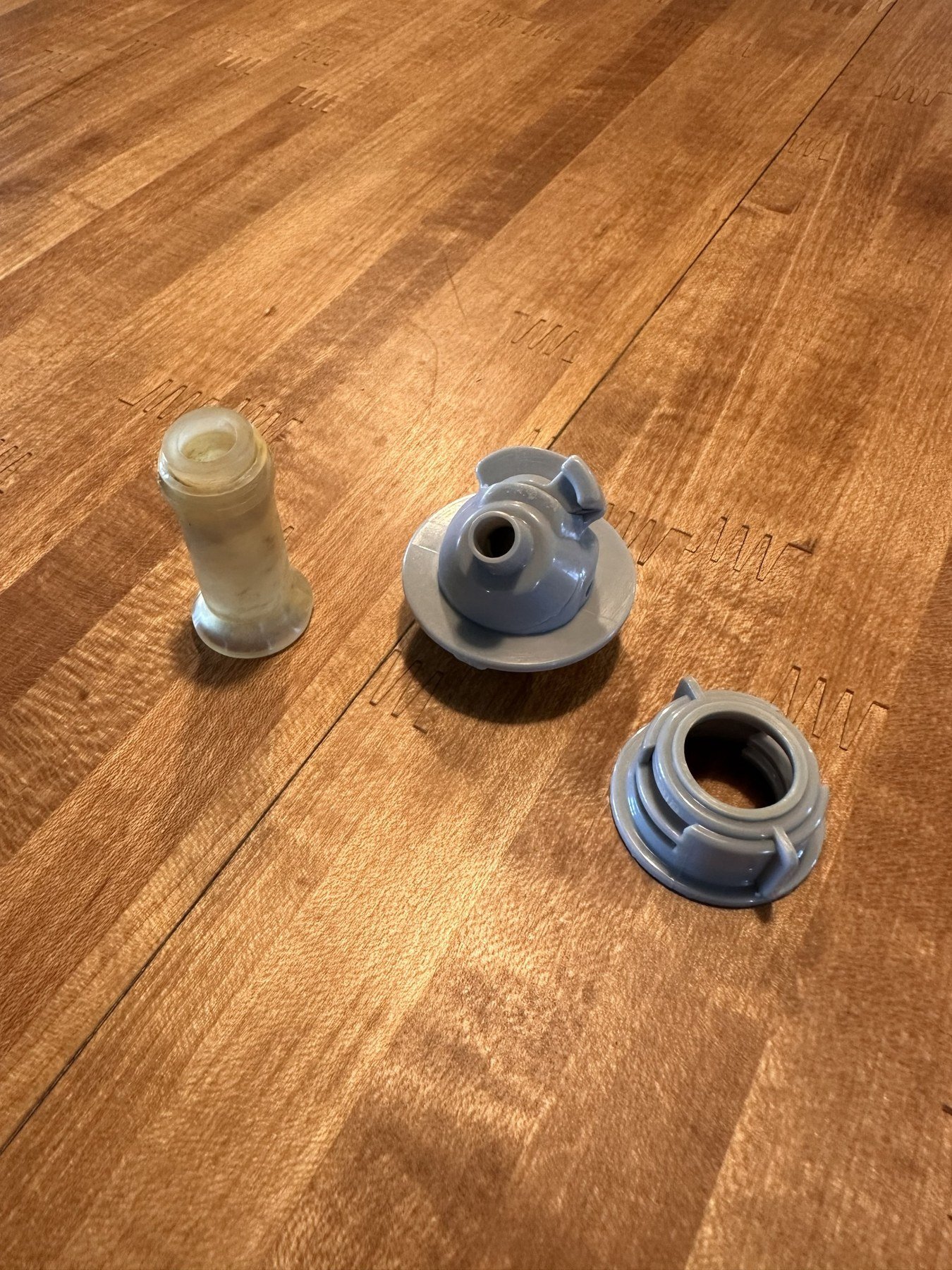 Gray upper dispenser, gray locking collar, and translucent outlet stem arranged on a wood surface