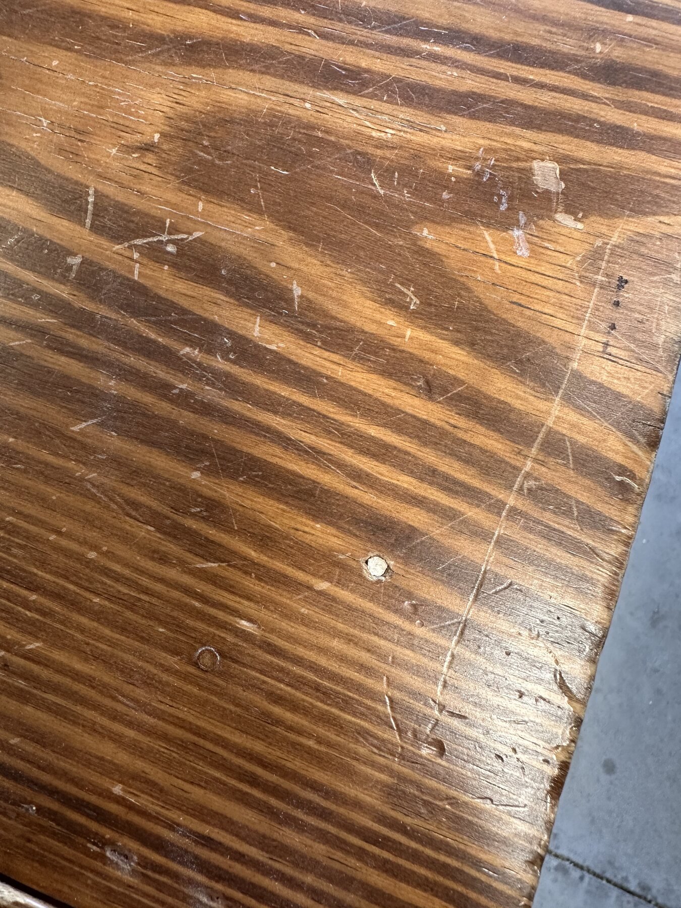 Close-up of scratches and pale worn spots in the tabletop finish