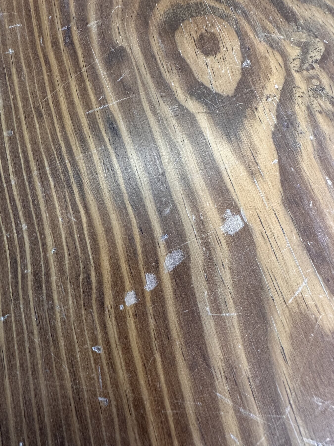 Close-up of the table's dark growth rings, knots, and surface wear