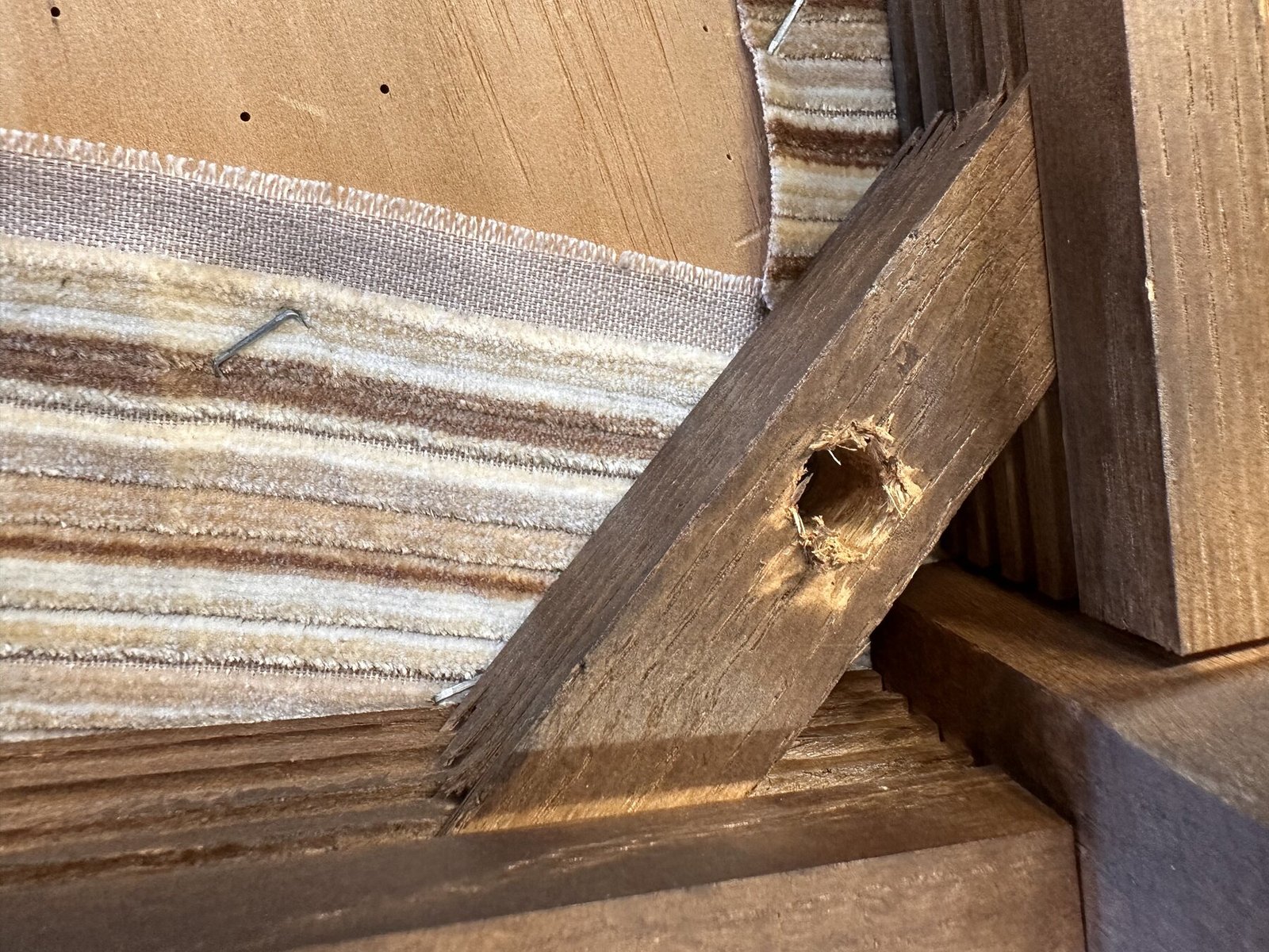 Damaged drilled hole in a wooden corner brace beneath a chair