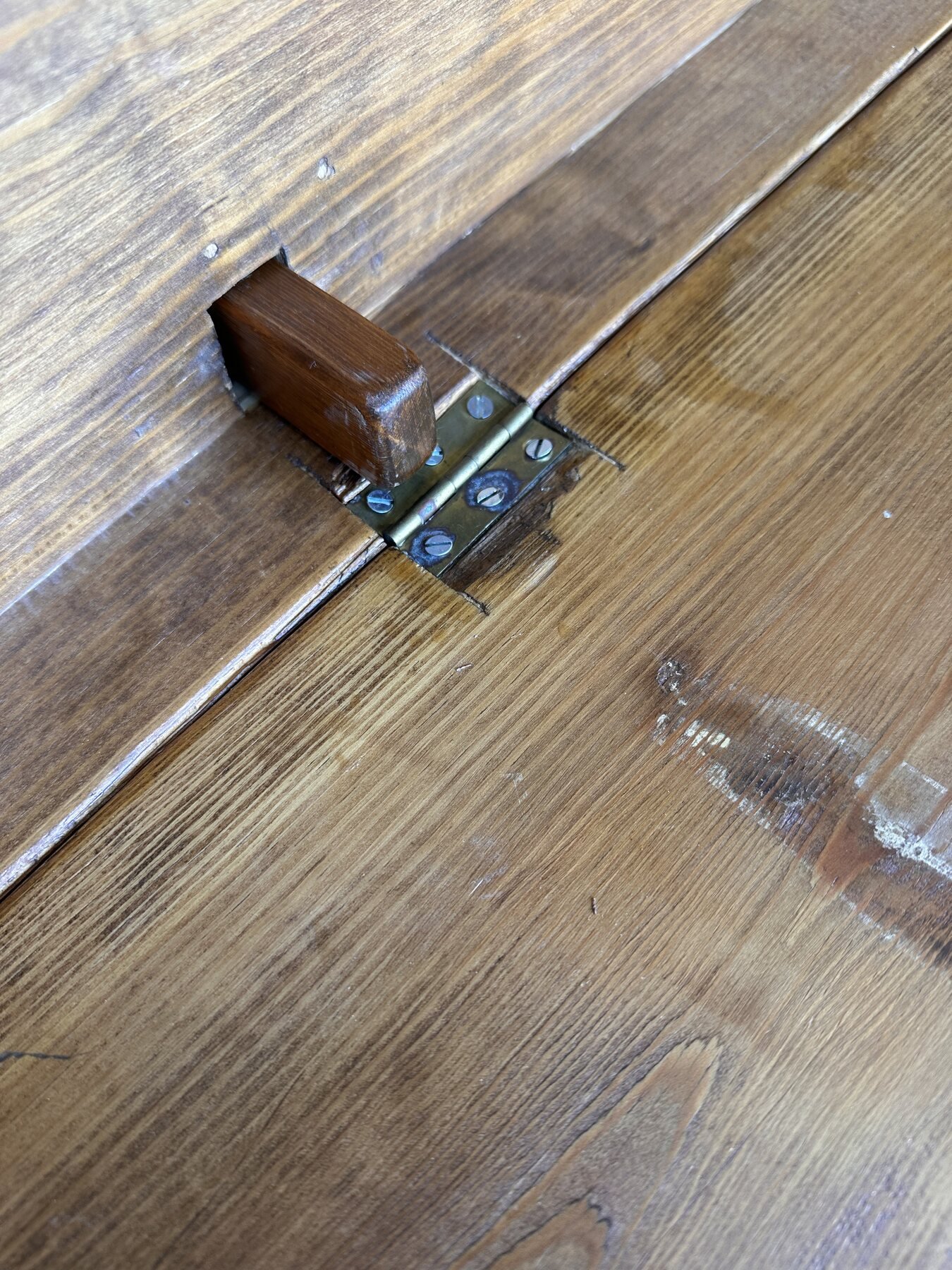 Wooden leaf-support brace extending through a rectangular opening beside a drop-leaf hinge