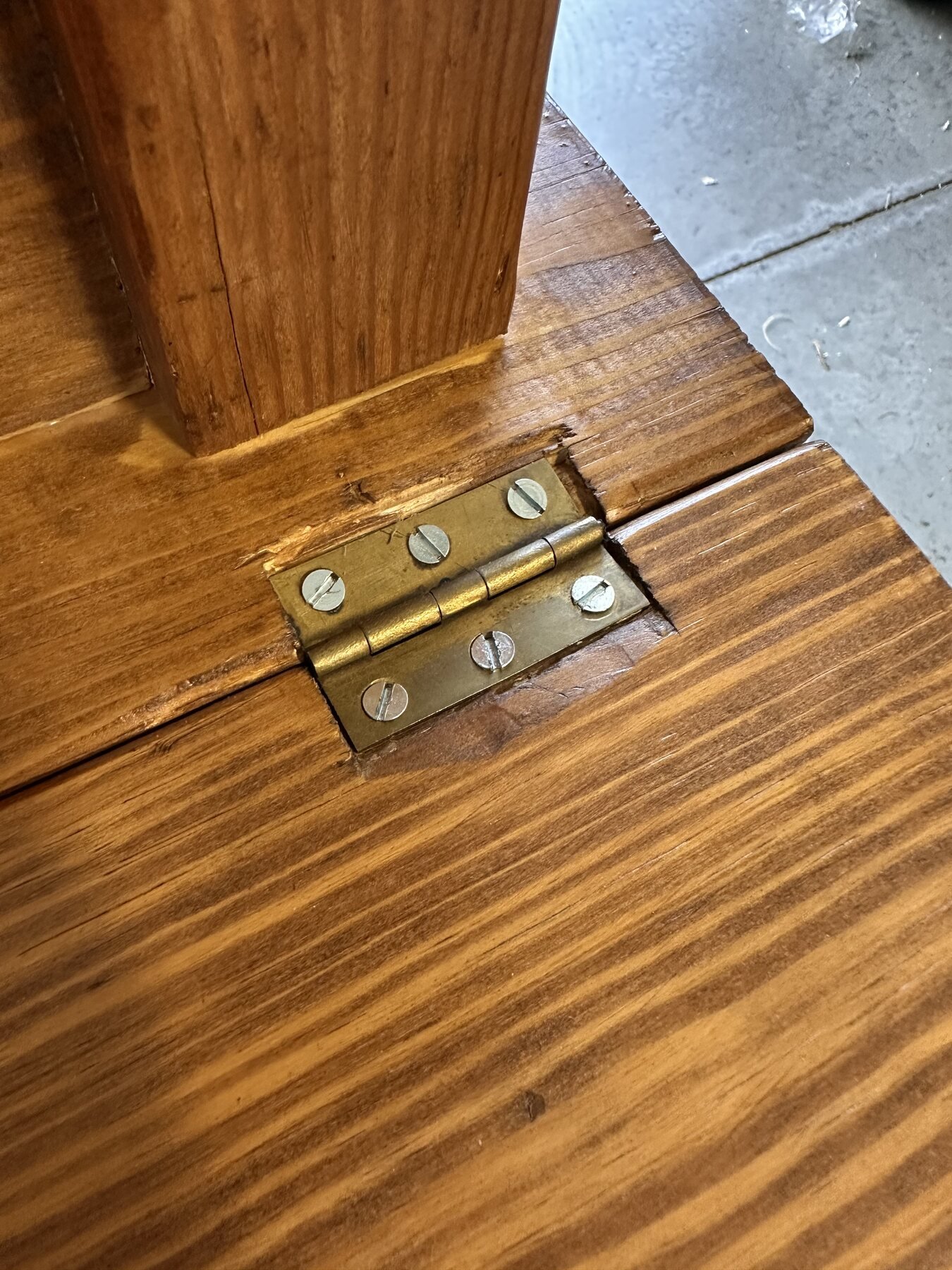 Drop-leaf hinge near a table leg showing mortise edges and surface wear