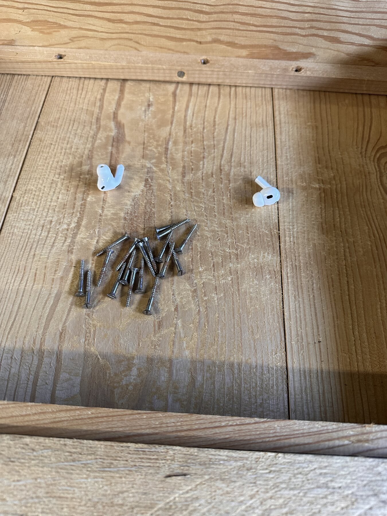 Pile of successfully removed slotted flathead screws resting on the underside of the table