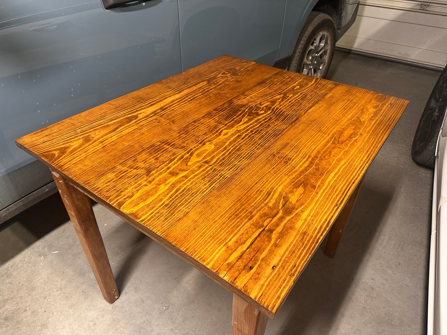 The $25 drop-leaf table glowing warmly in the garage after its fifth clear coat