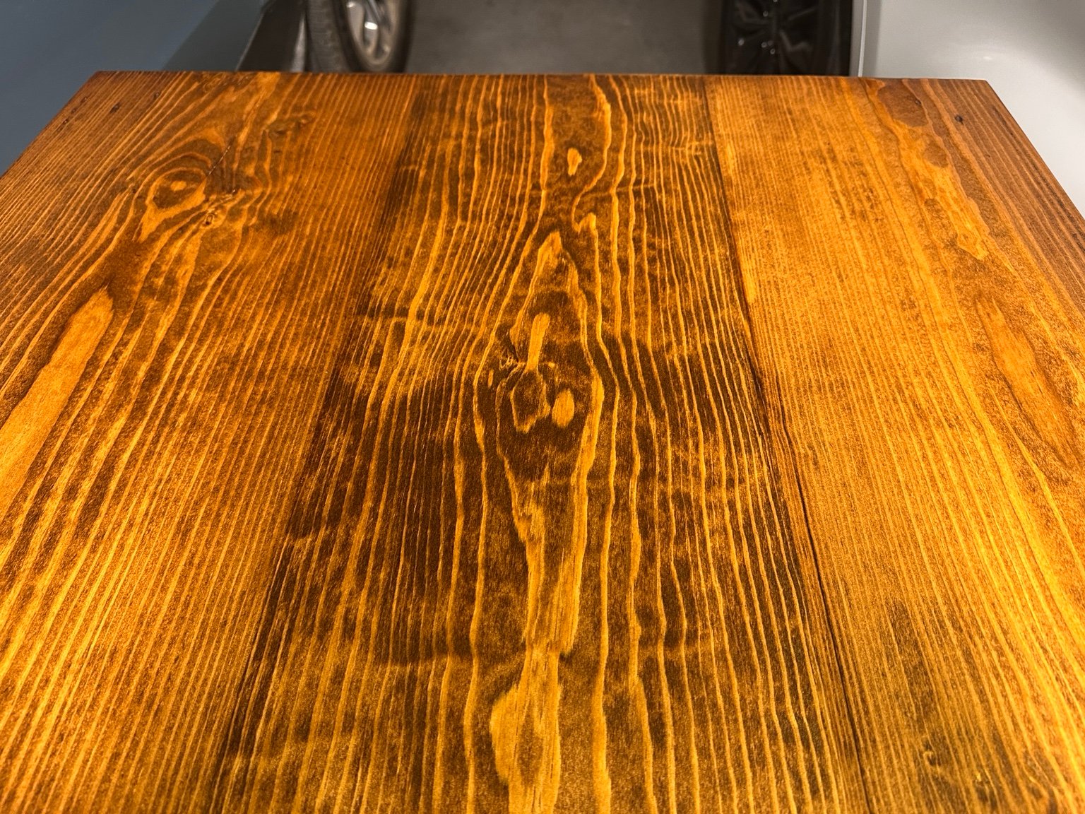 Close-up of dark and amber pine grain beneath the fifth polyurethane coat