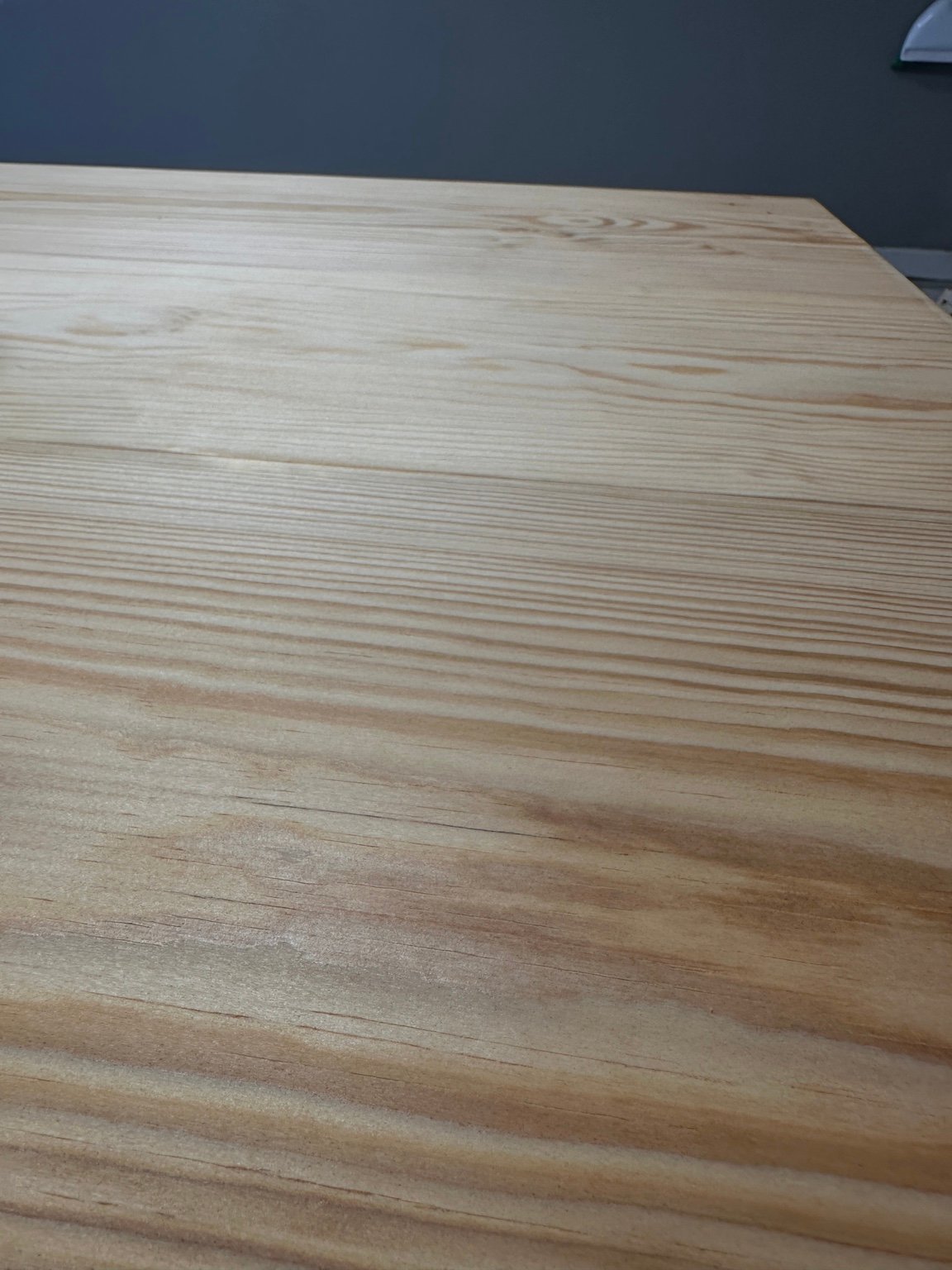Close view across the pale tabletop showing long grain lines before staining