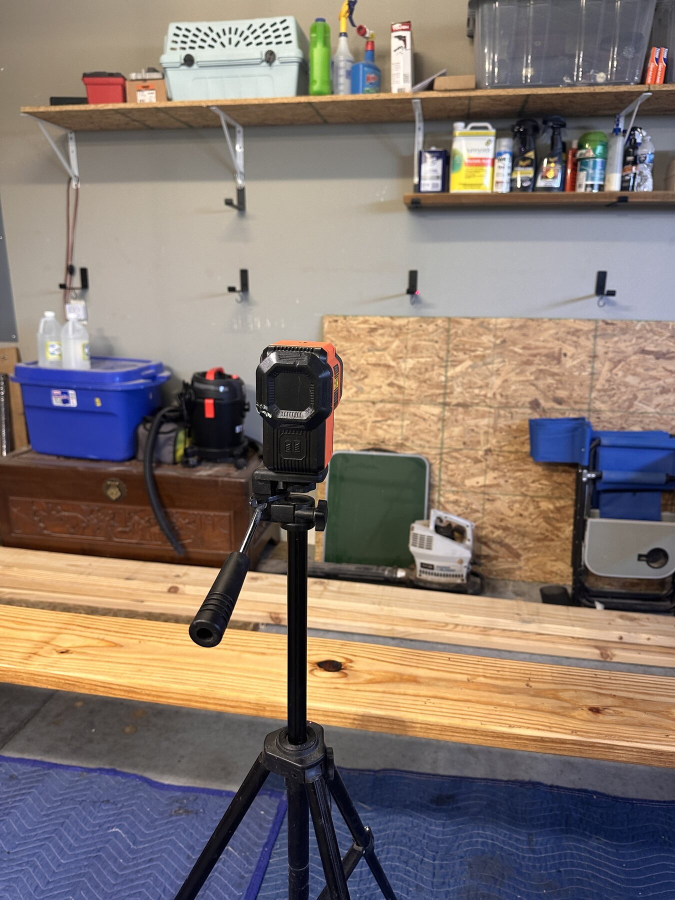 Laser level on tripod aimed at shelf brackets