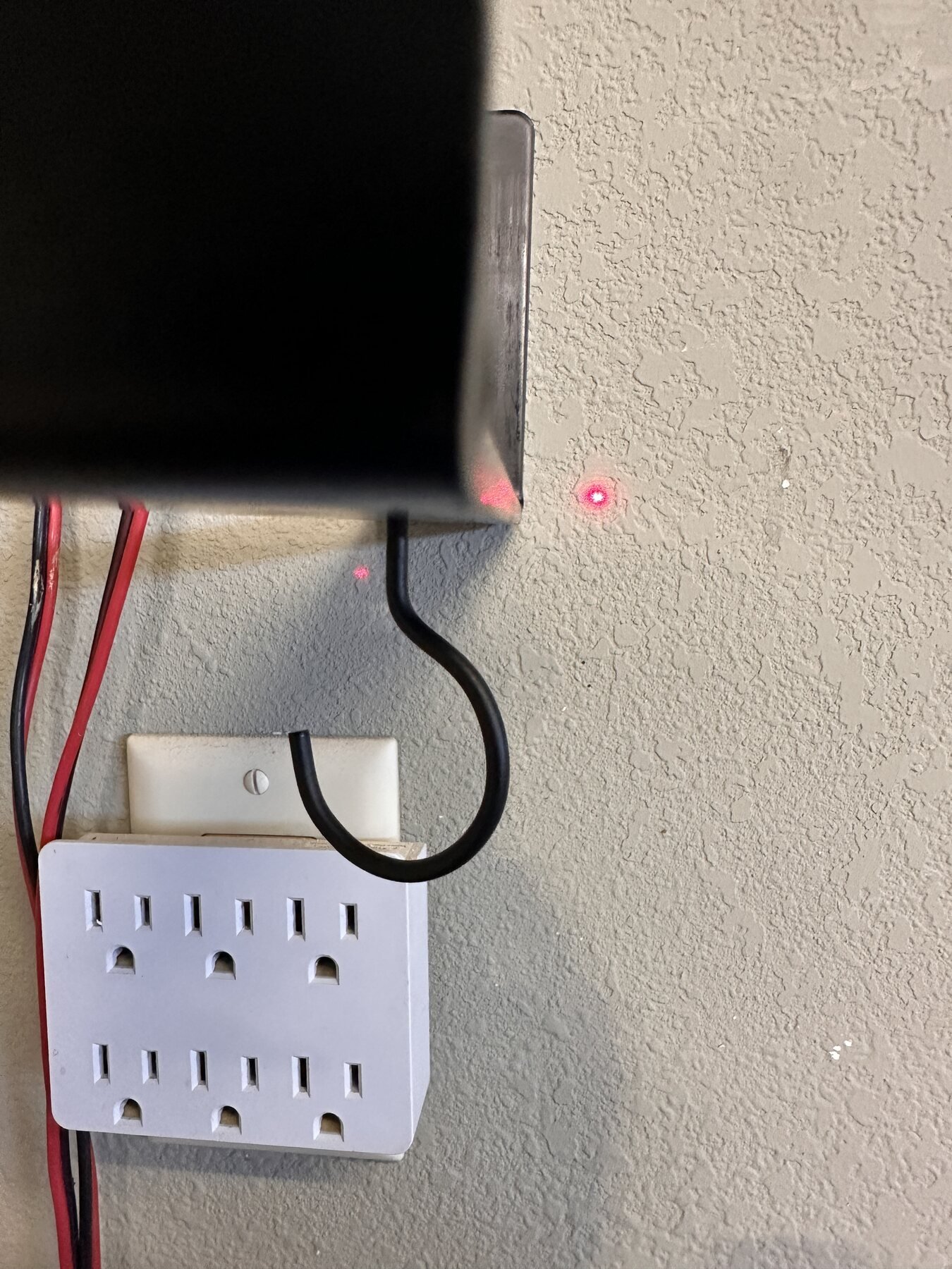 End shelf bracket near outlet with red laser dot on wall