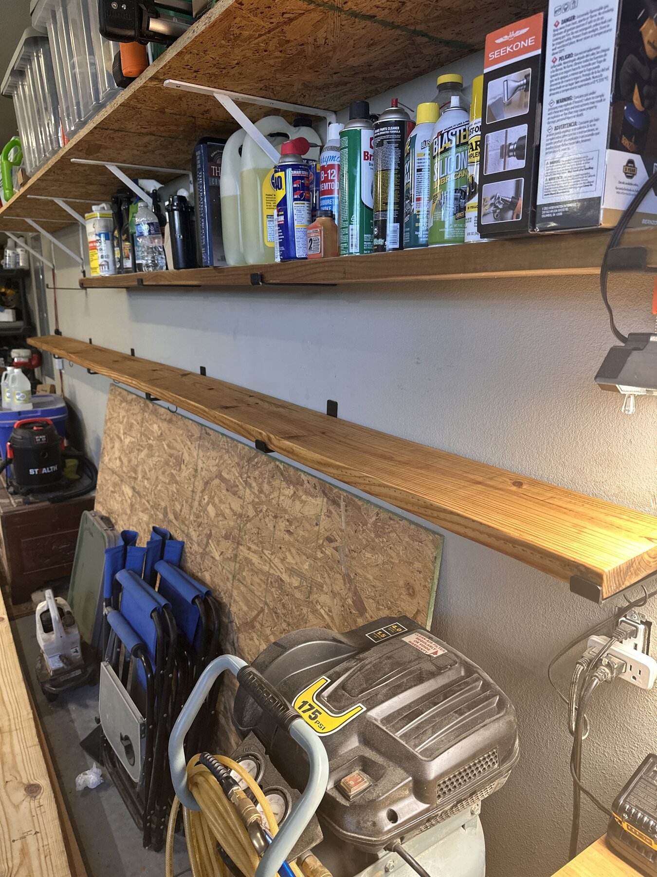 Finished pine board resting on black brackets in the garage