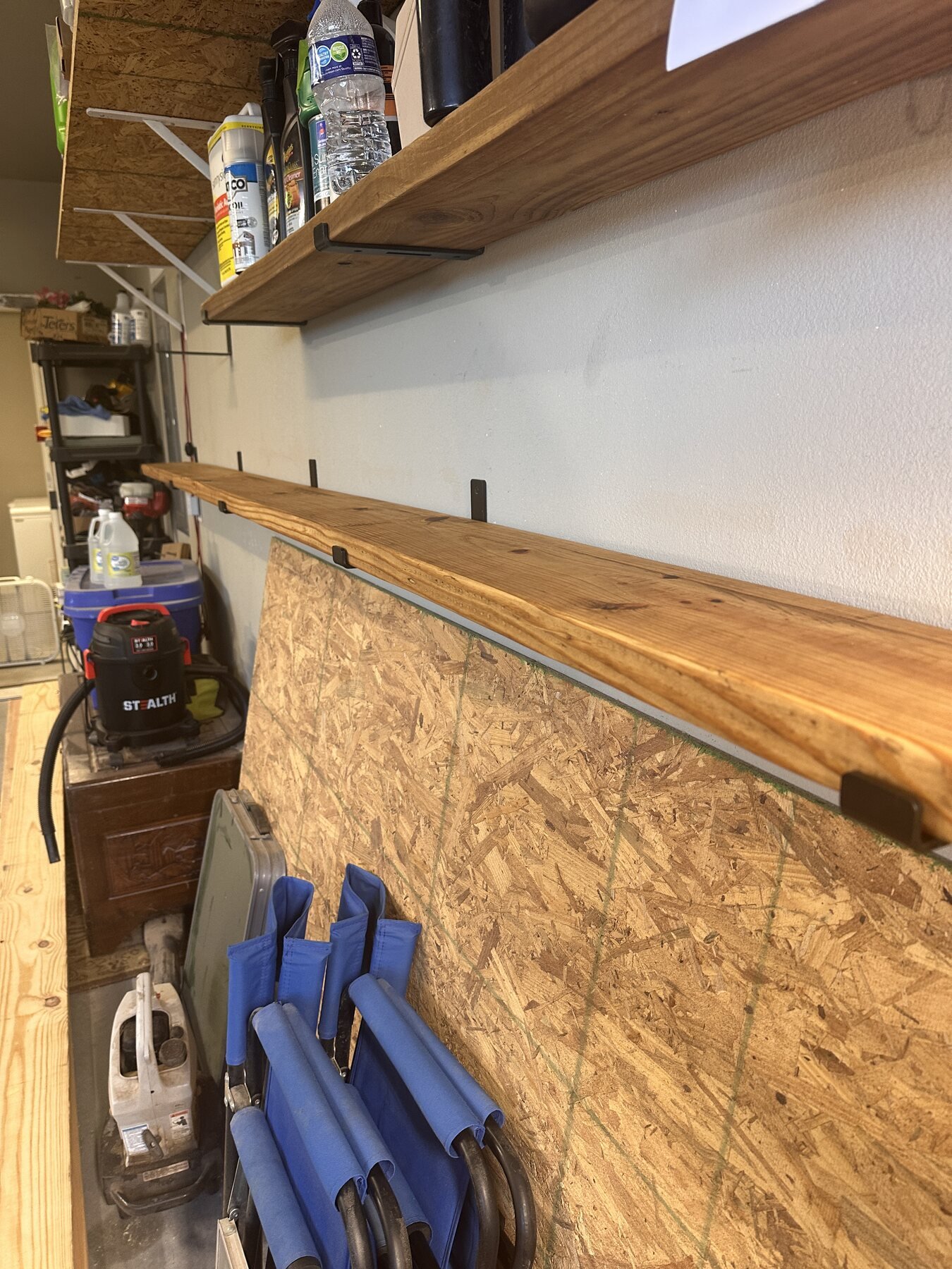 Finished pine board mounted as the first new garage shelf