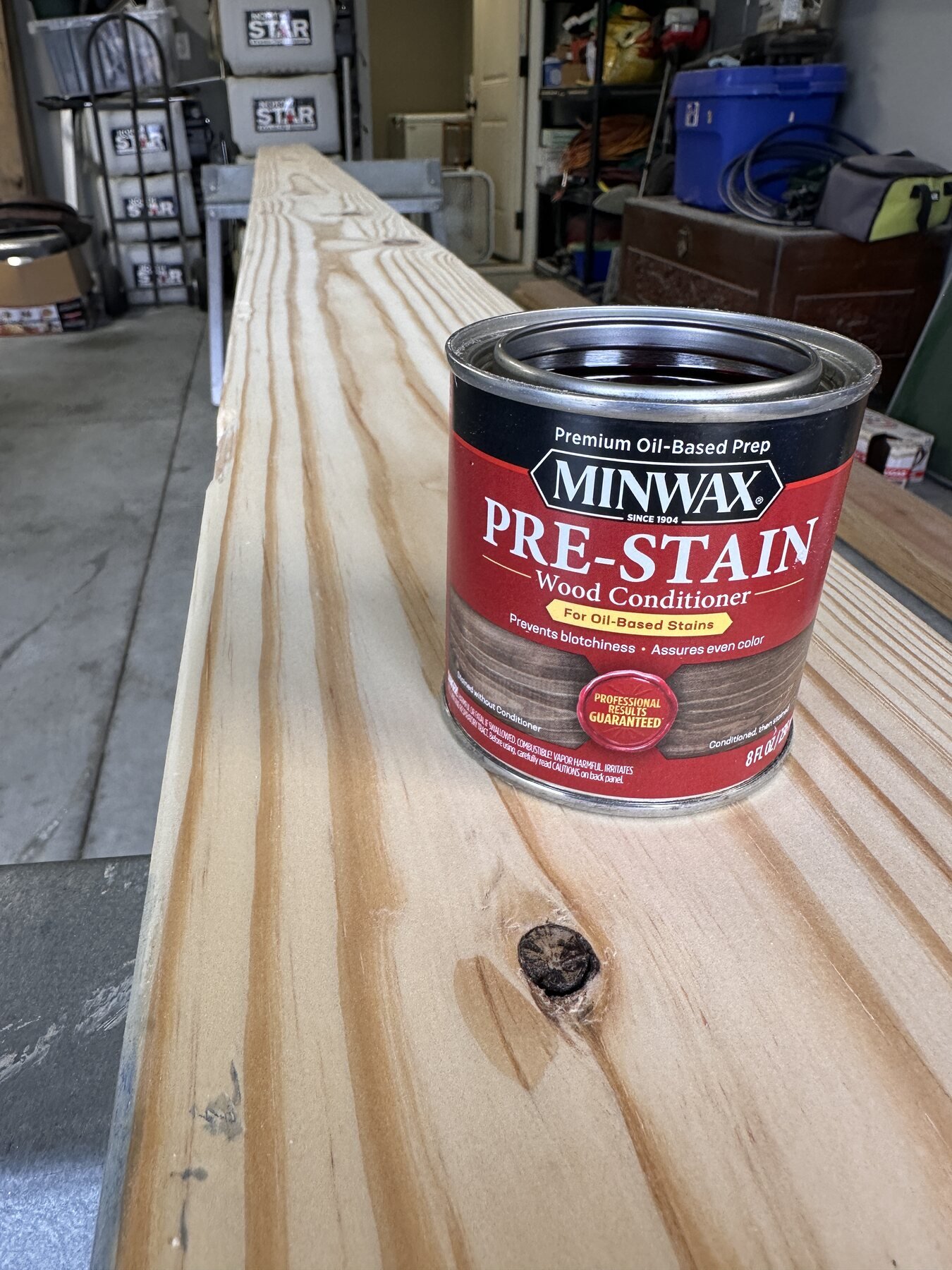 Open can of Minwax pre-stain wood conditioner sitting on the long pine board