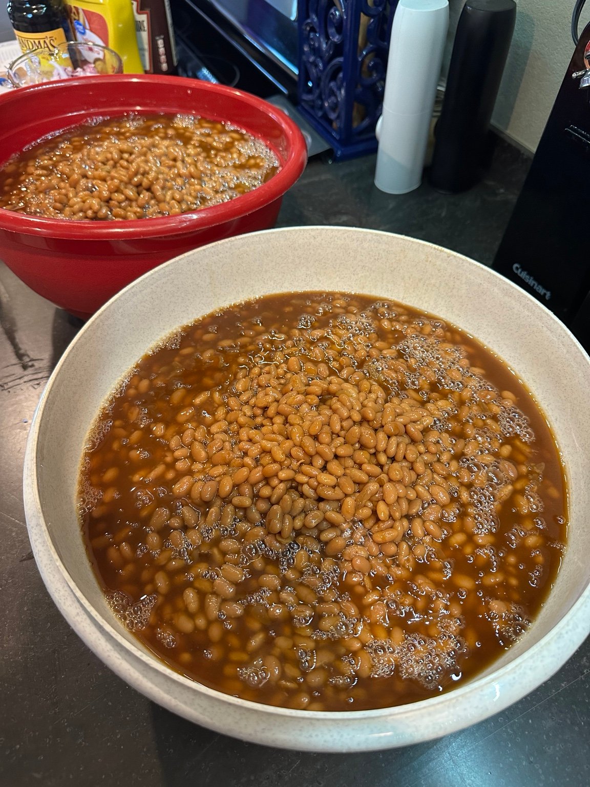Two very large kitchen bowls filled nearly to the top with baked beans