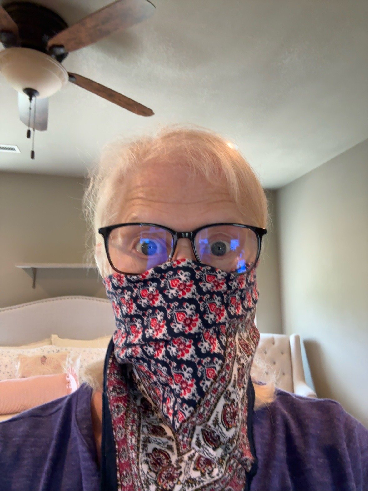 Janet wearing glasses and a patterned kerchief over her nose and mouth while chopping onions