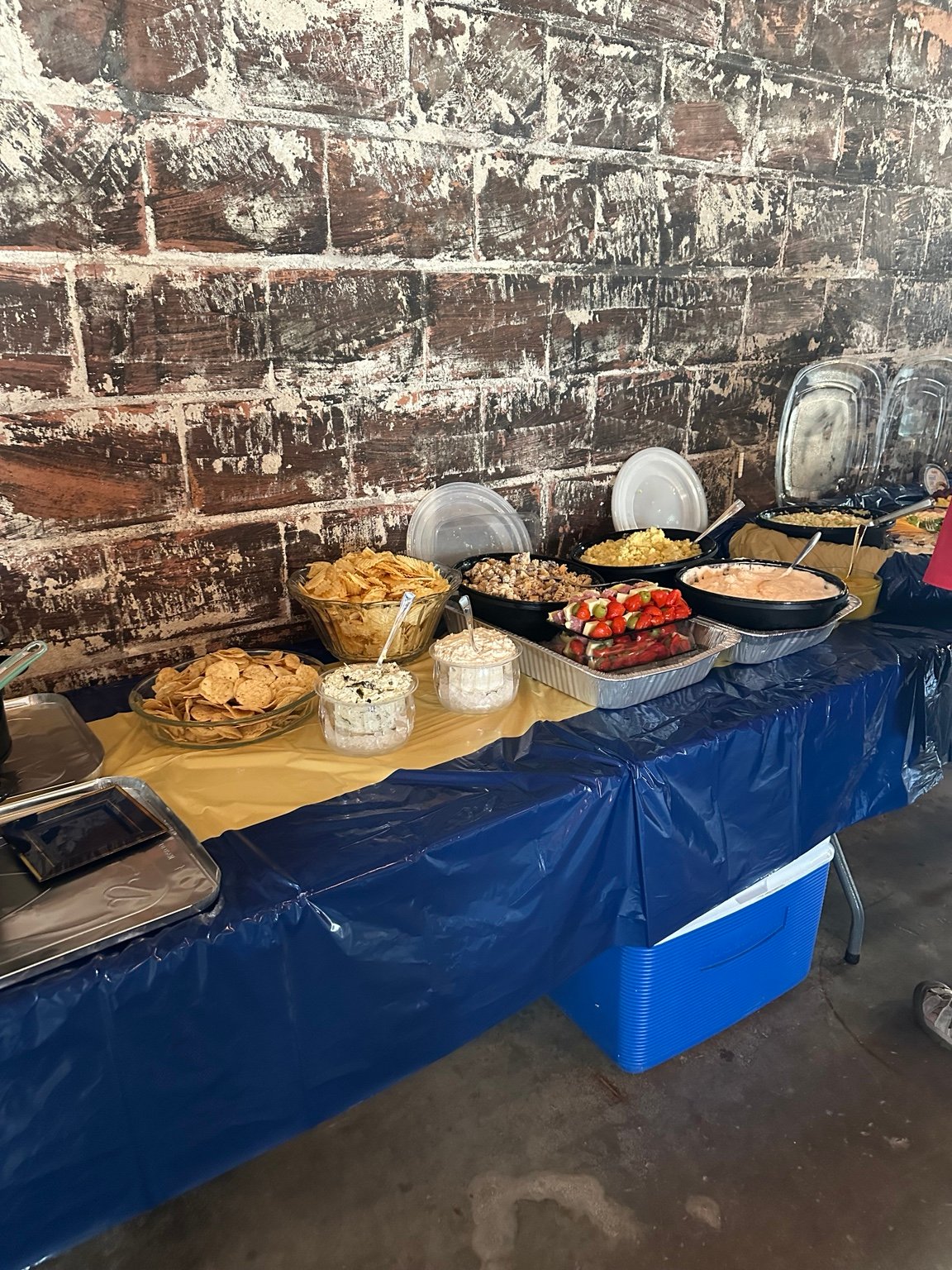 A long anniversary buffet table filled with chips, salads, dips, and hot dishes