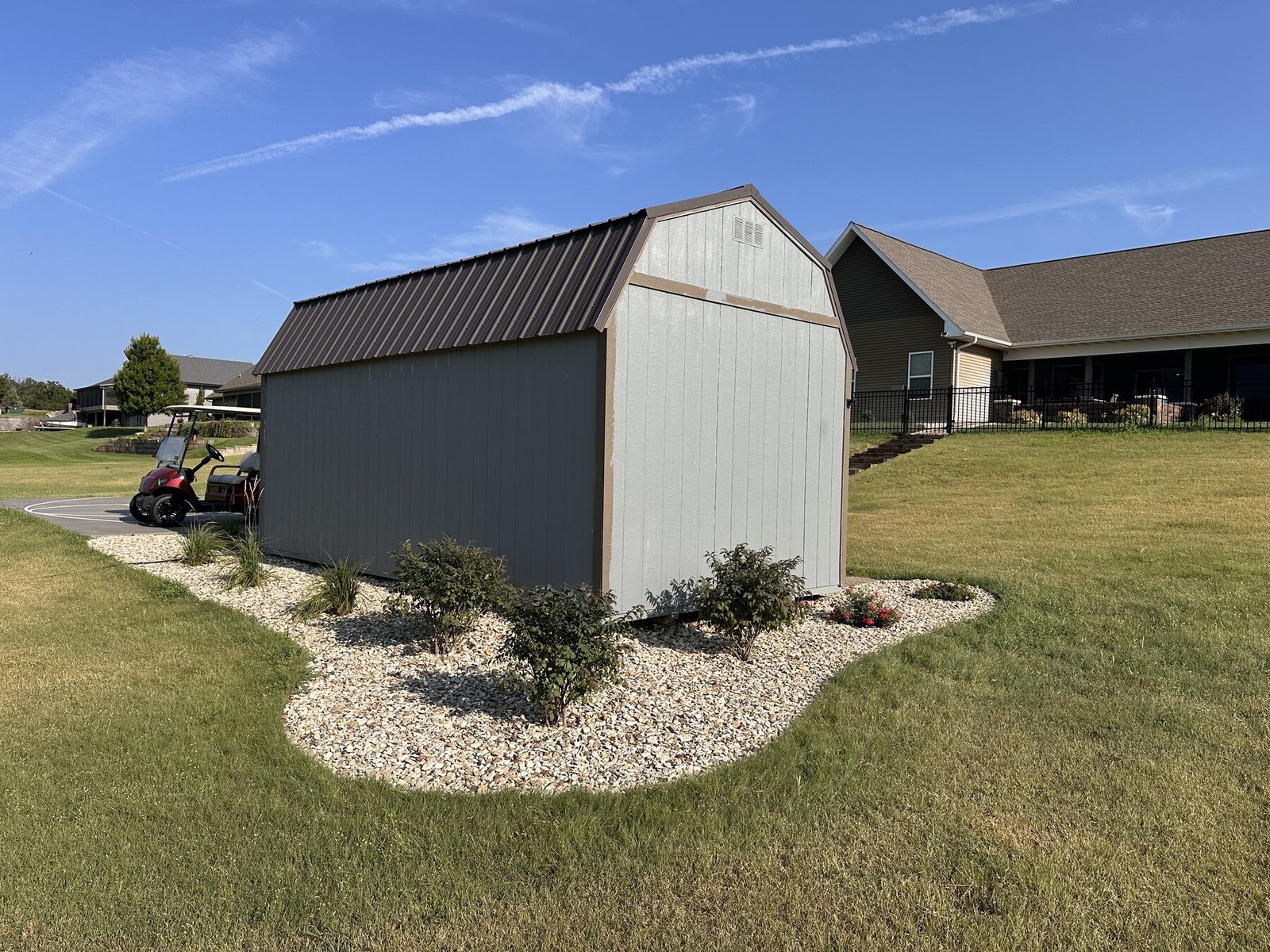 Side view of the shed garden with shrubs, roses, and grasses in record heat