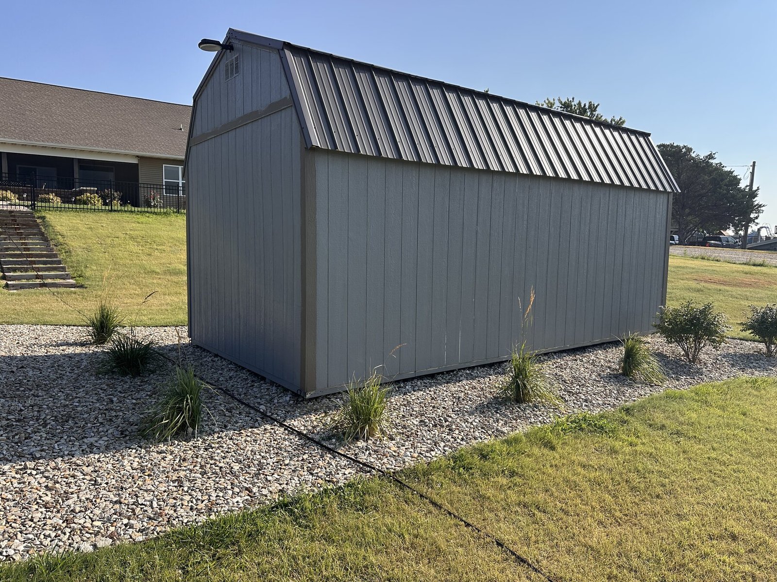 Long side of the shed with decorative grasses and burning bushes in the rock bed