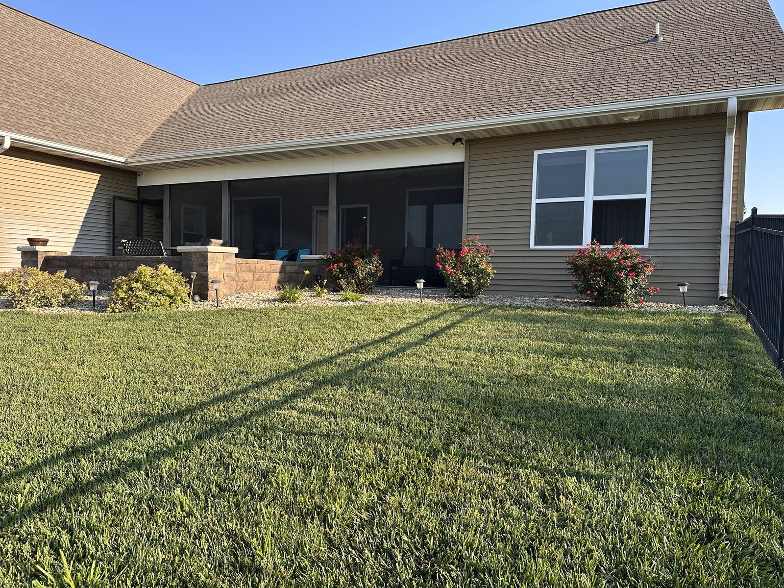 Wide quiet view of the back of the house and garden beds from across the lawn