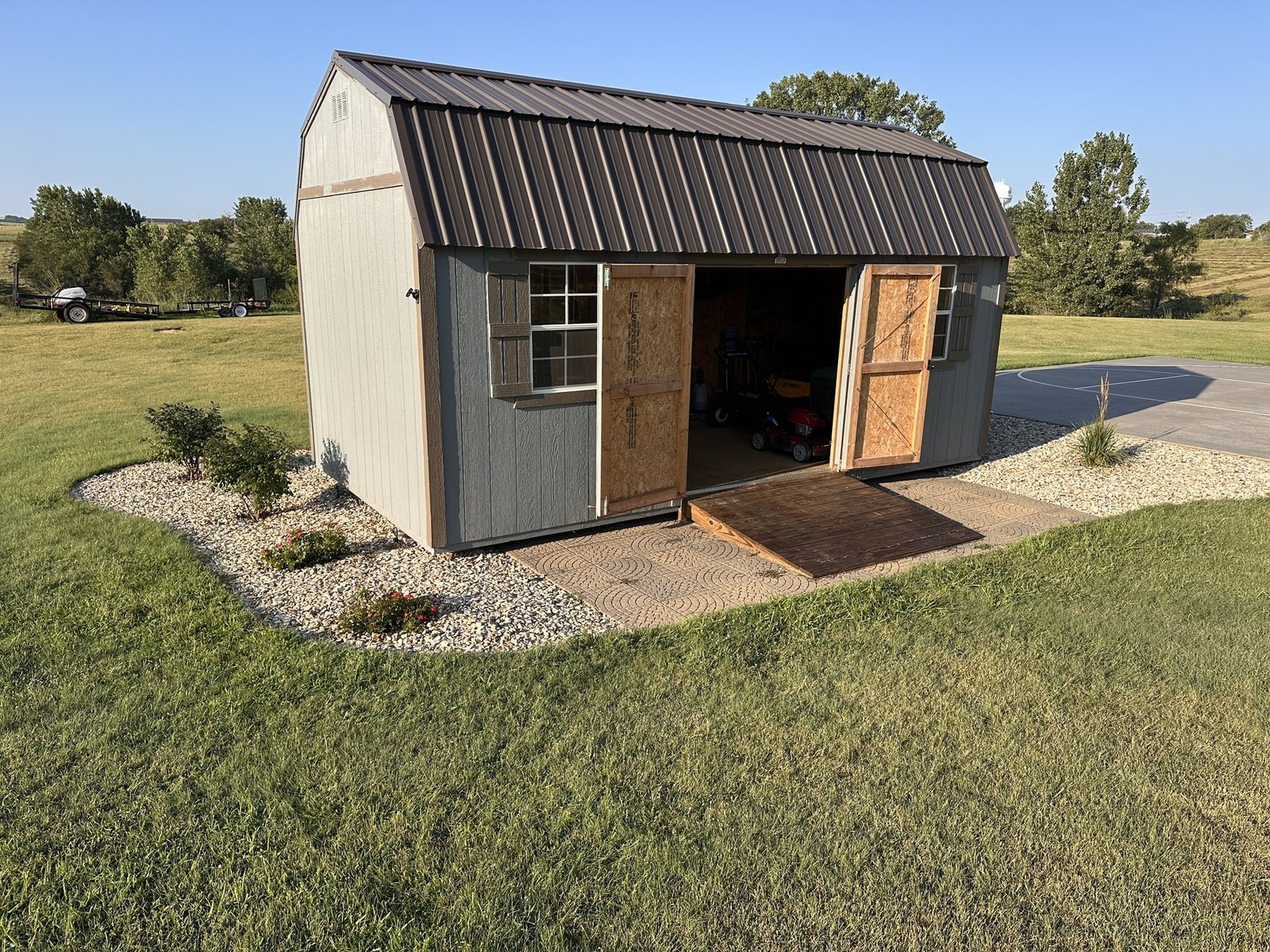 Wide morning view of the backyard shed, its open doors, and the surrounding garden beds