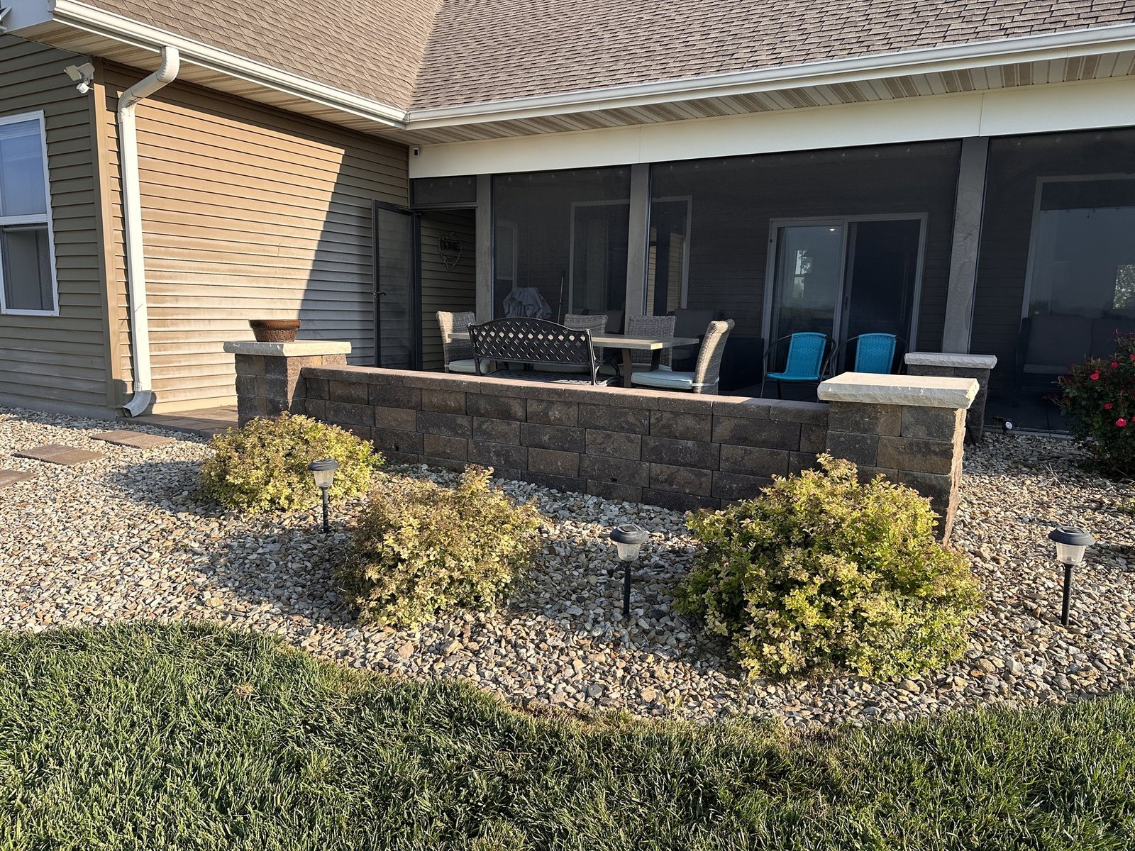 Three unnamed spirea bushes in the rock bed in front of the screened porch wall